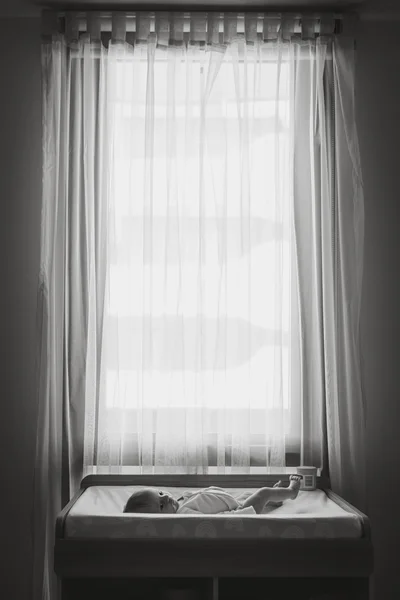 Newborn baby on change mat in front of window